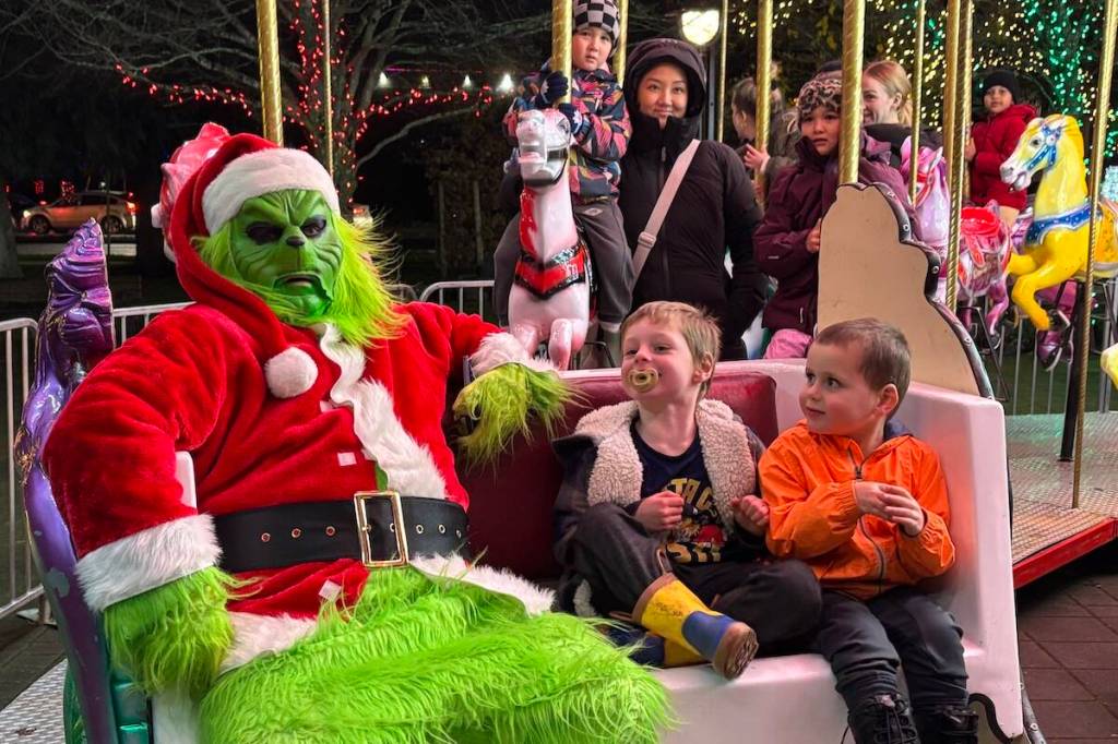 The Grinch rides the carousel in Langford&rsquo;s Veterans Memorial Park with James and Miguel Woodburn. (Ben Fenlon/Goldstream Gazette)